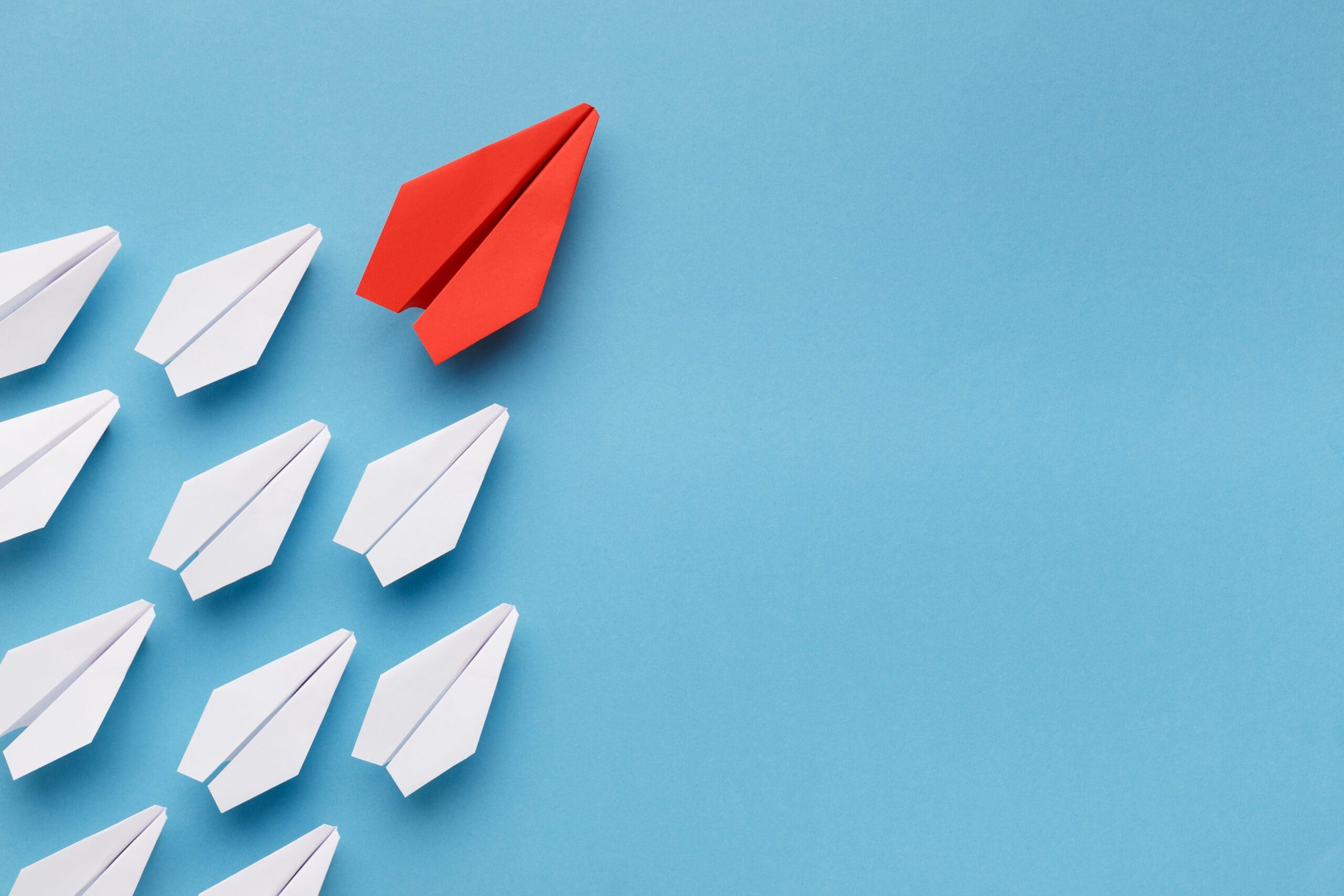 Blue paper boat leading among white ships Blue paper boat leading among white ships